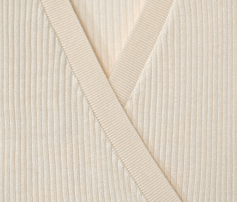 Gros plan sur une veste en tricot enfant de couleur crème.