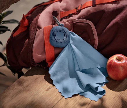 Une linge de toilette d’extérieur bleue accrochée à un sac à dos.