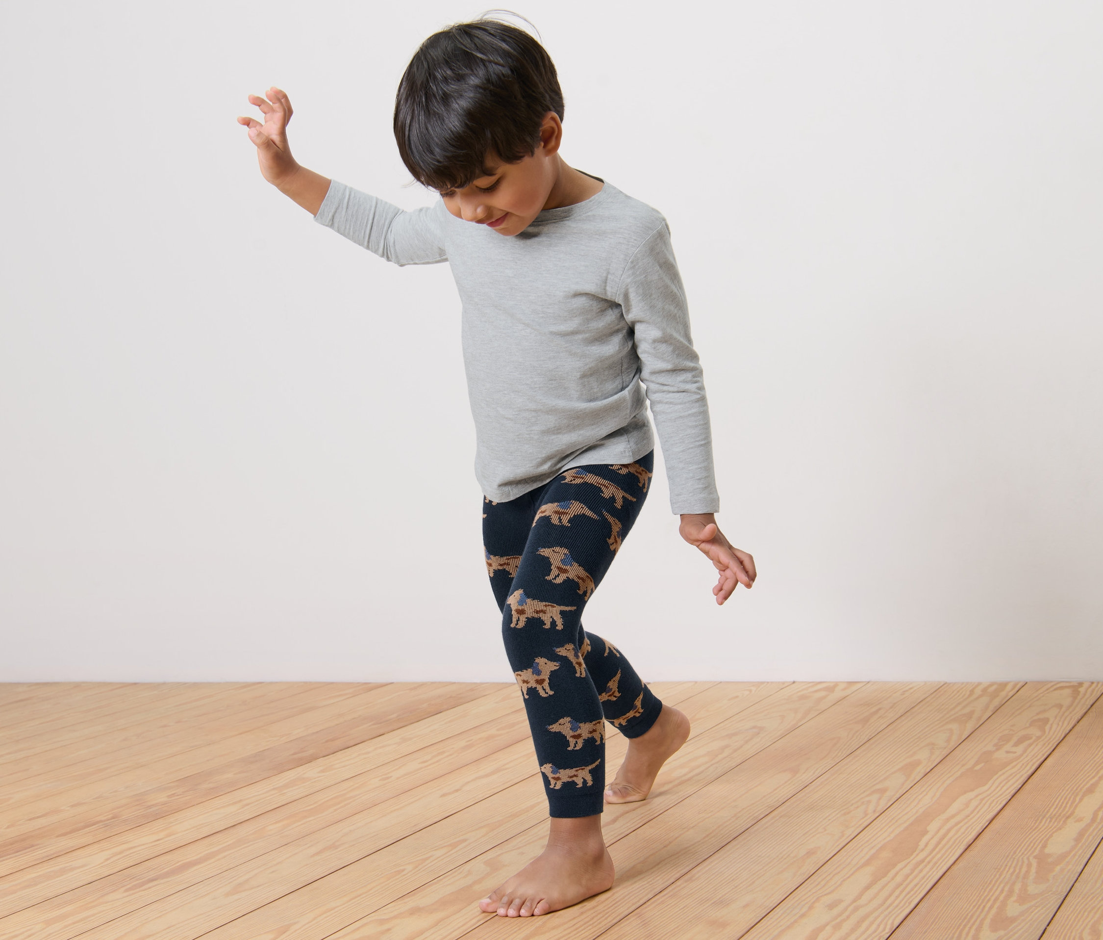 Un garçon danse en leggings thermiques avec un motif de teckels.