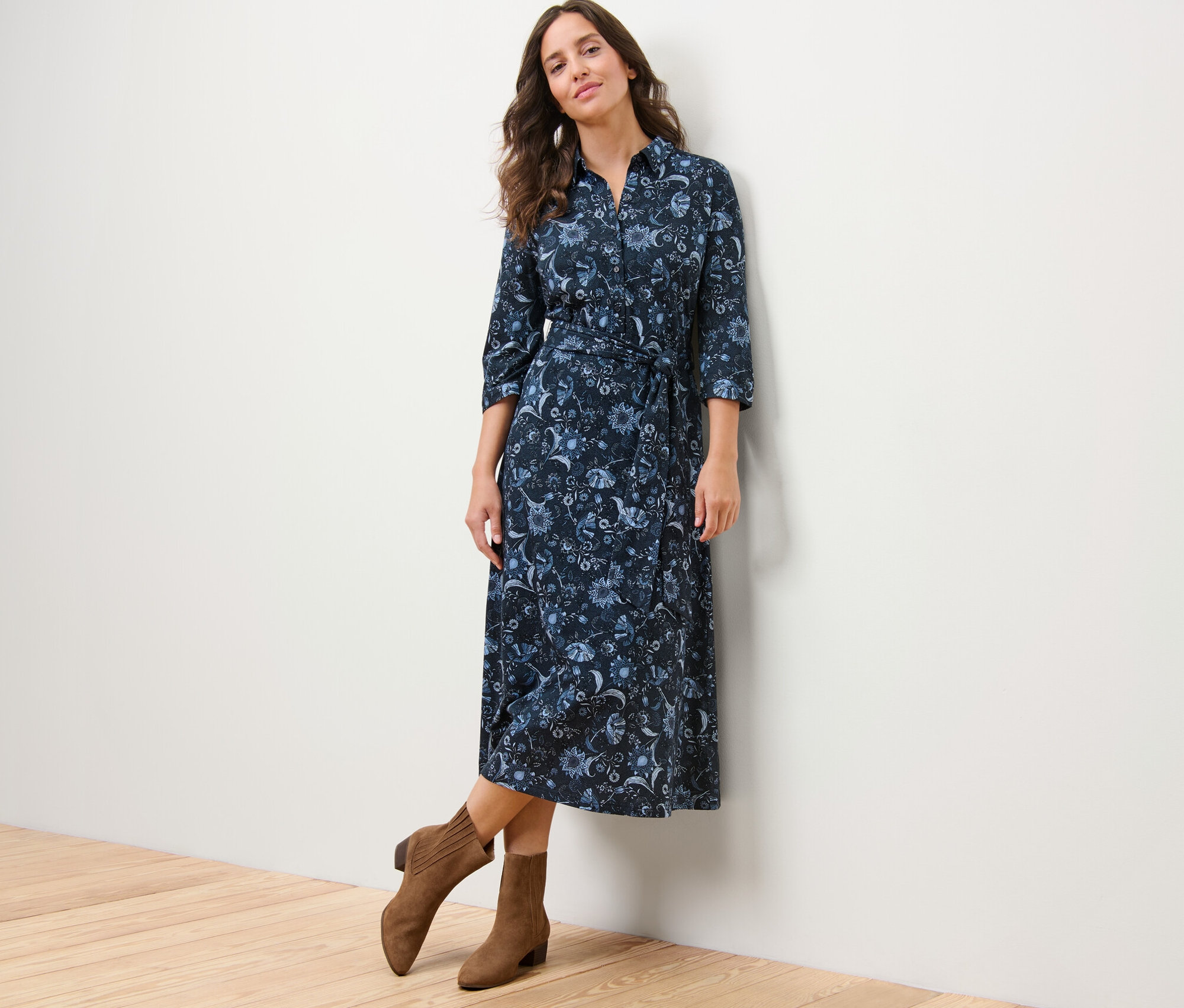 Femme posant dans une robe en jersey imprimée et des bottes marron.