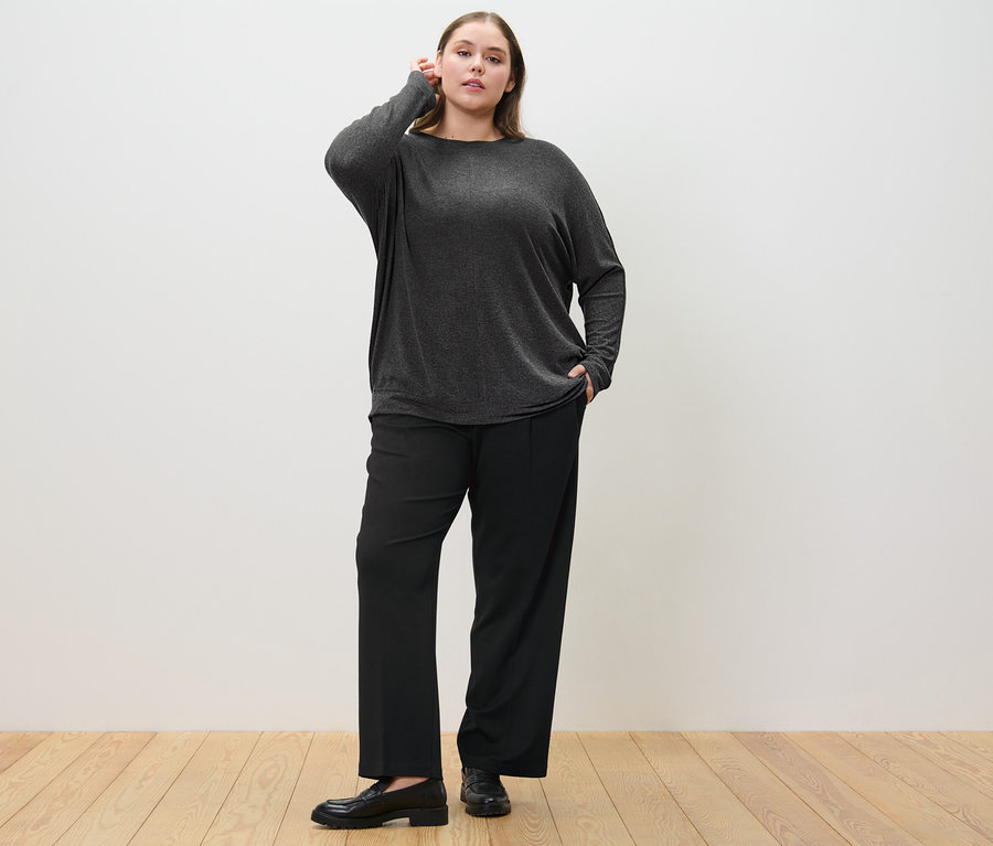 Femme posant en pantalon en jersey confortable et pull manches chauve-souris.