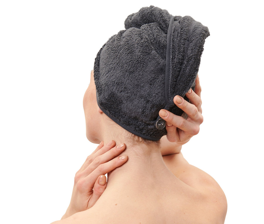 Femme ajustant une serviette turban anthracite sur sa tête.