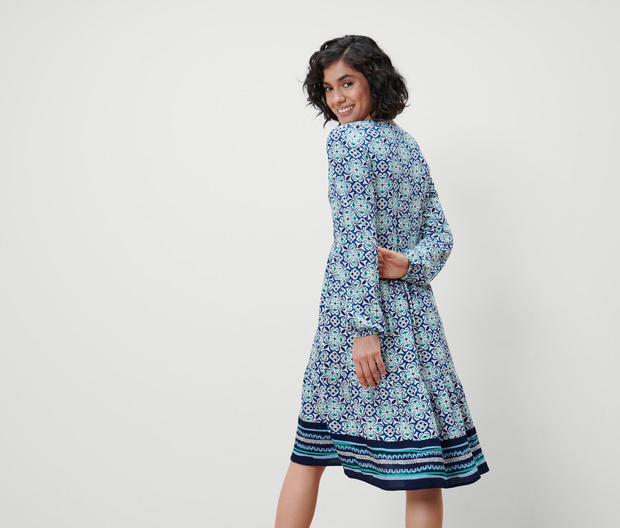 Femme regardant par-dessus son épaule portant une robe tissée à imprimé intégral.