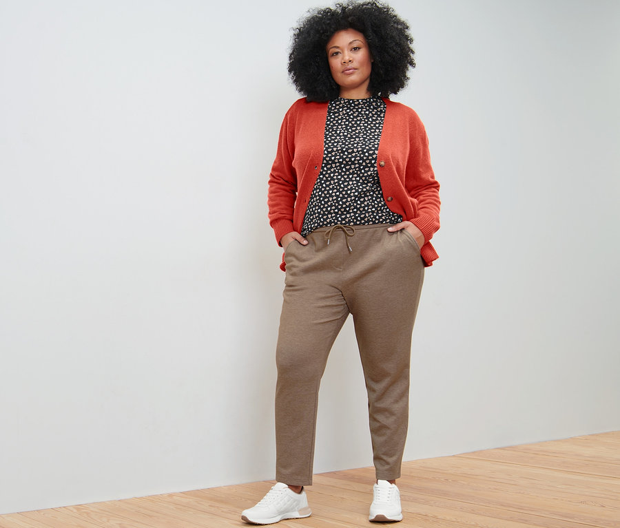 Femme posant en pantalon de jogging beige, t-shirt manches longues avec imprimé intégral et cardigan à encolure en V.