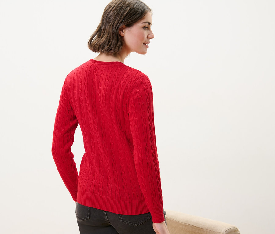 Une femme vue de dos porte un pull en maille torsadée rouge.