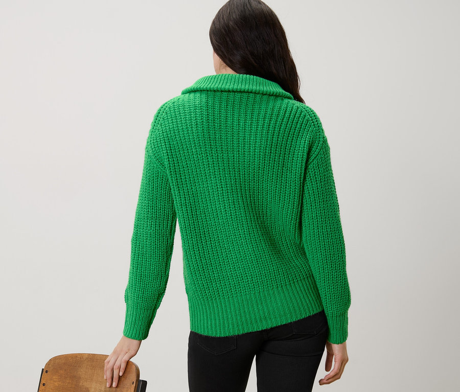 Femme vue de dos portant un pull camionneur vert en grosse maille.