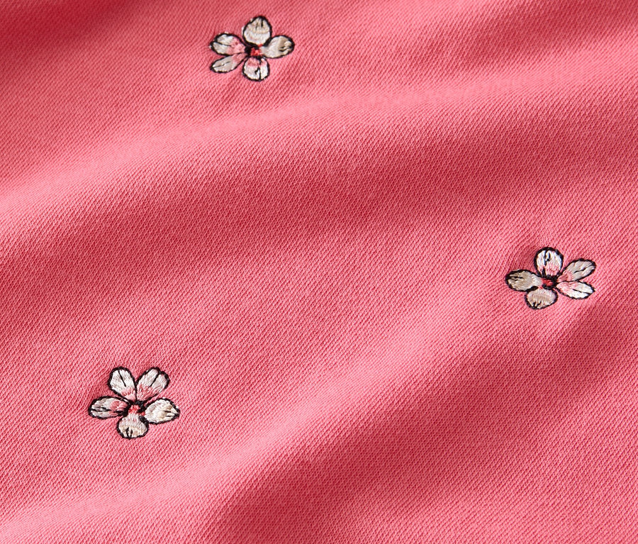 Gros plan d'un sweatshirt brodé rose.