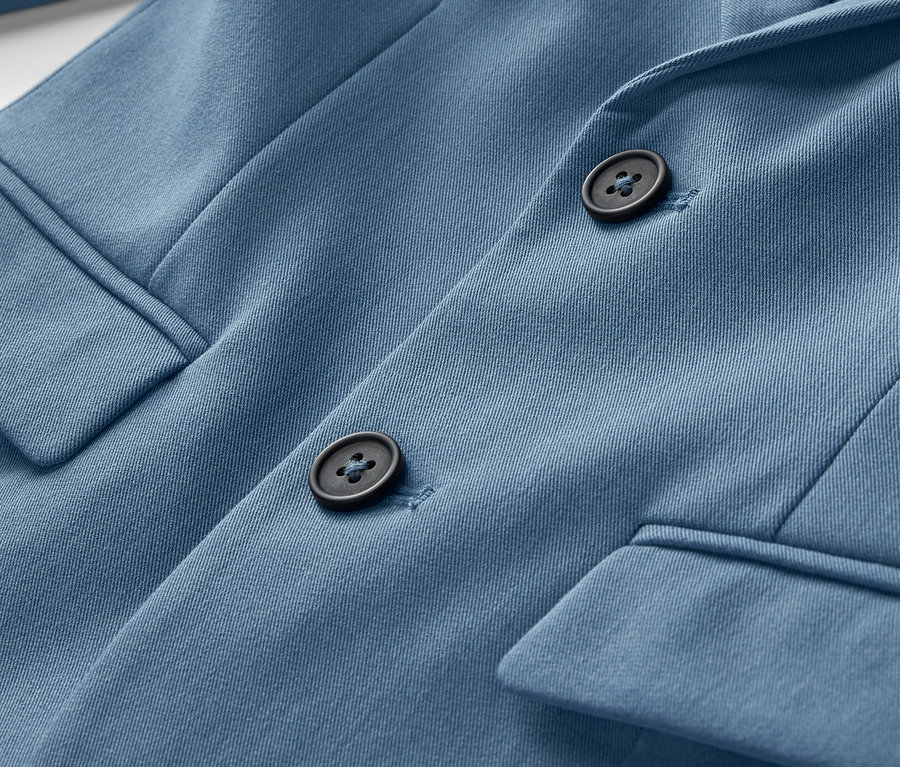 Détail d'un veston bleu pour enfant avec des boutons.