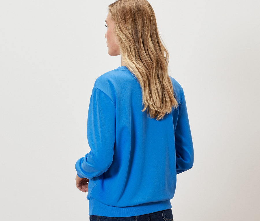 Femme vue de dos portant un sweat-shirt bleu cobalt.