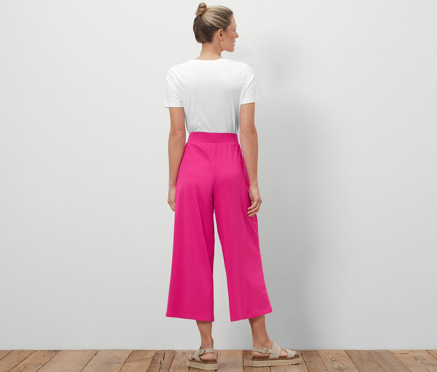 Une femme portant un chignon se tient dos à la caméra et porte un pantalon jersey.