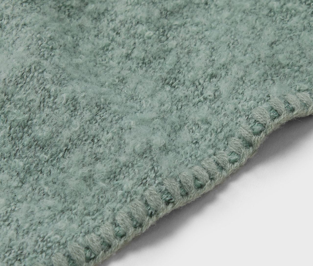 Gros plan d'un tapis vert clair avec une bordure décorative.