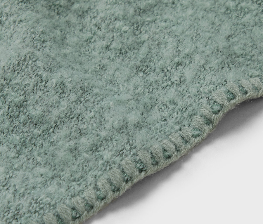 Gros plan d'un tapis vert clair avec une bordure décorative.