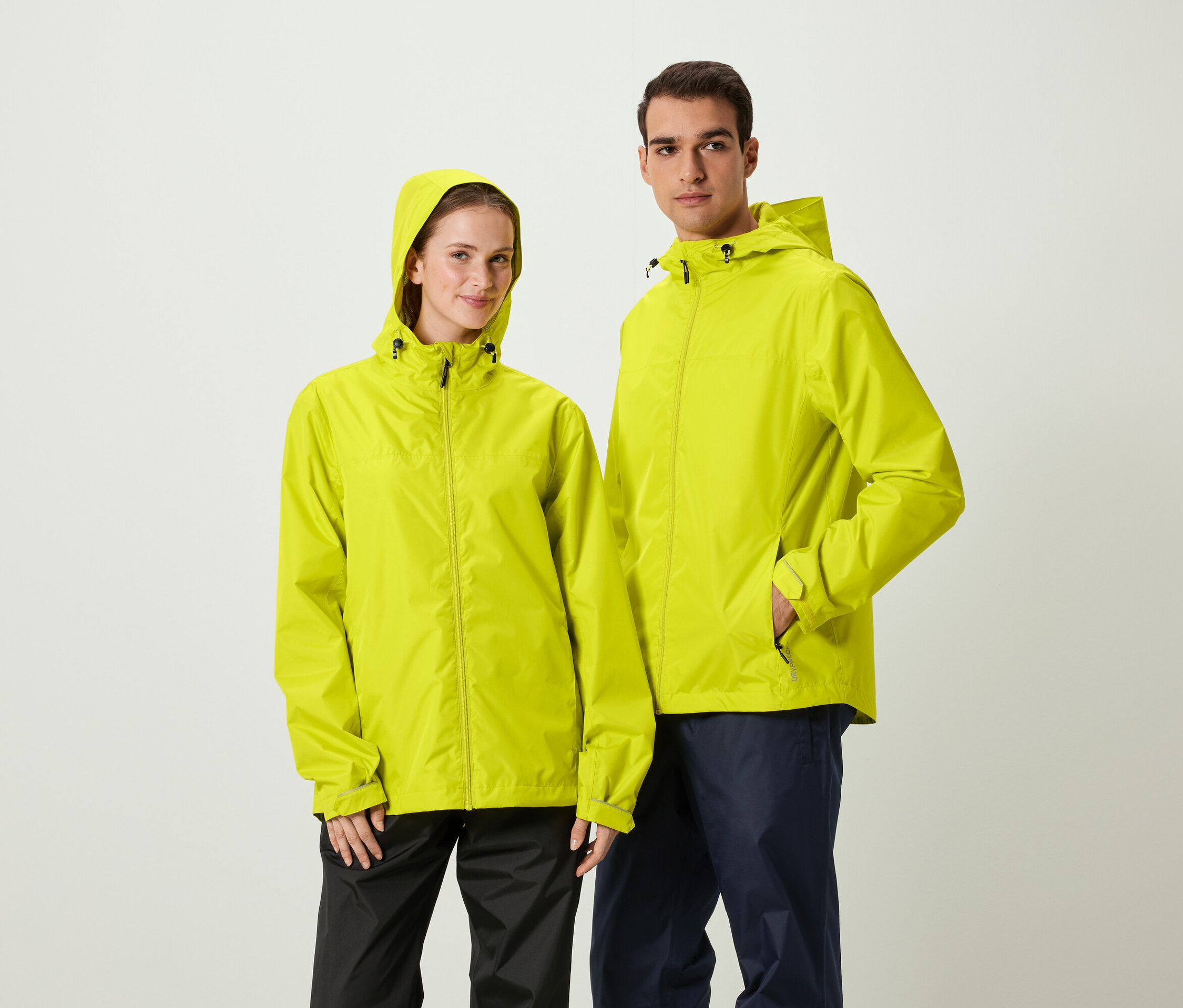 Un homme et une femme se tiennent côte à côte et portent des vestes de pluie jaunes à capuche.