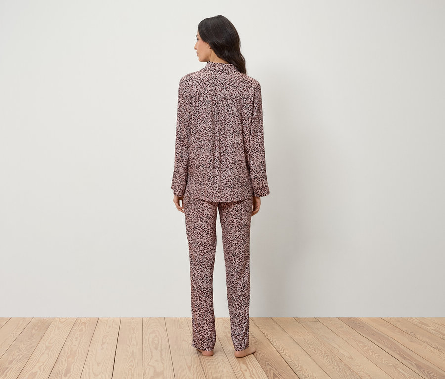 Une femme se tient dos à la caméra et porte un pyjama rose à motif animal.