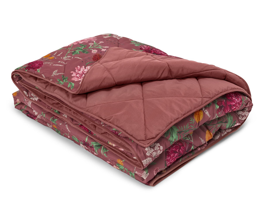 Couverture matelassée pliée avec motif floral et couleur bordeaux.