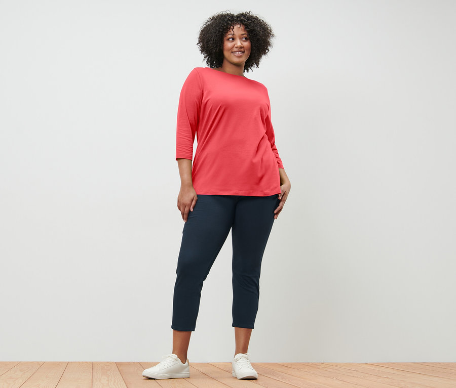 Femme posant en t-shirt manches 3/4 corail et pantalon bleu marine.