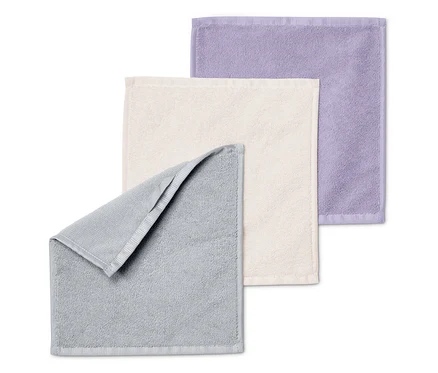 Trois serviettes pliées les unes sur les autres : grise, crème et violette.