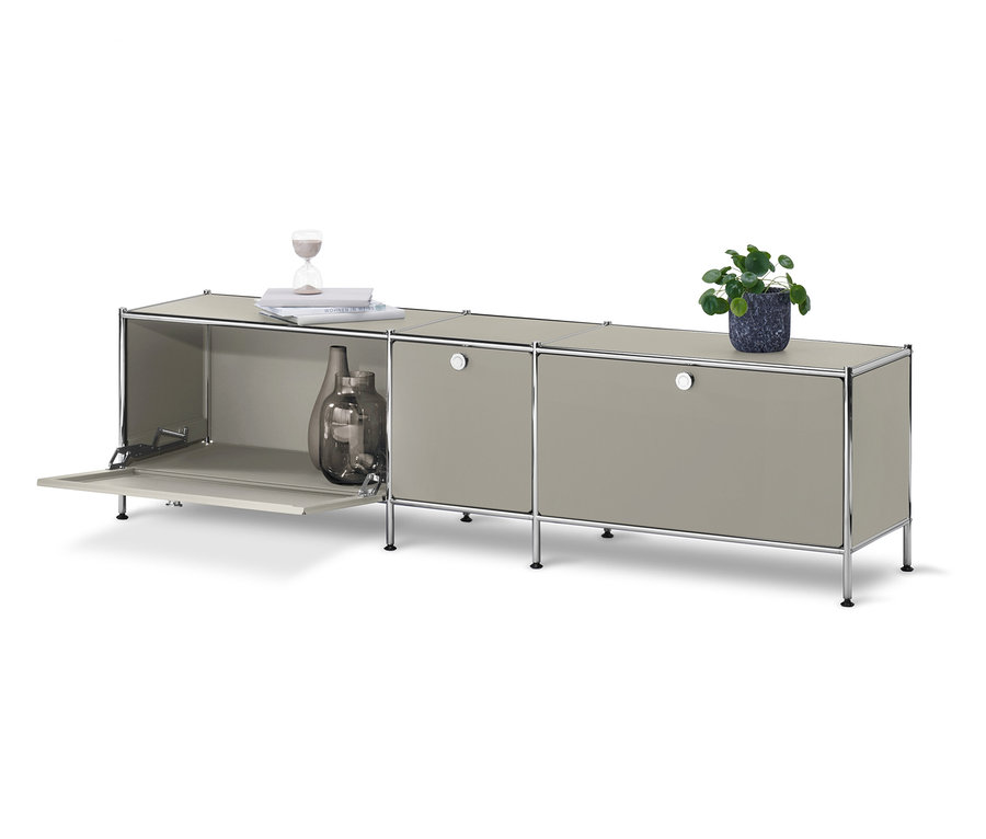Meuble bas « CN3 » gris avec 3 abattants, dont un ouvert avec des vases à l'intérieur.