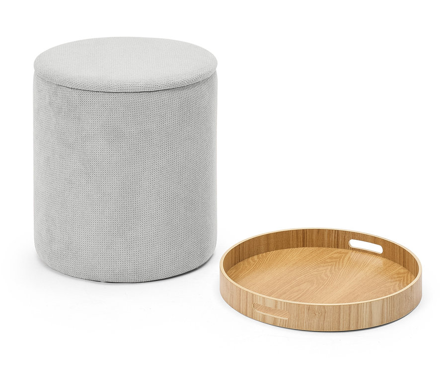 Un tabouret en tissu gris à côté d'un plateau rond en bois.