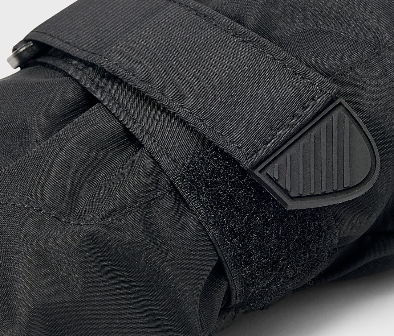 Gros plan d'un gant noir avec une fermeture Velcro et une extrémité de sangle en caoutchouc.