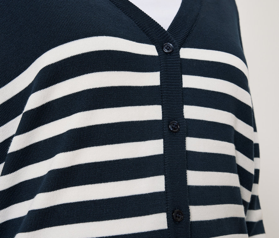 Détail d'un cardigan bleu marine à rayures blanches et boutons.