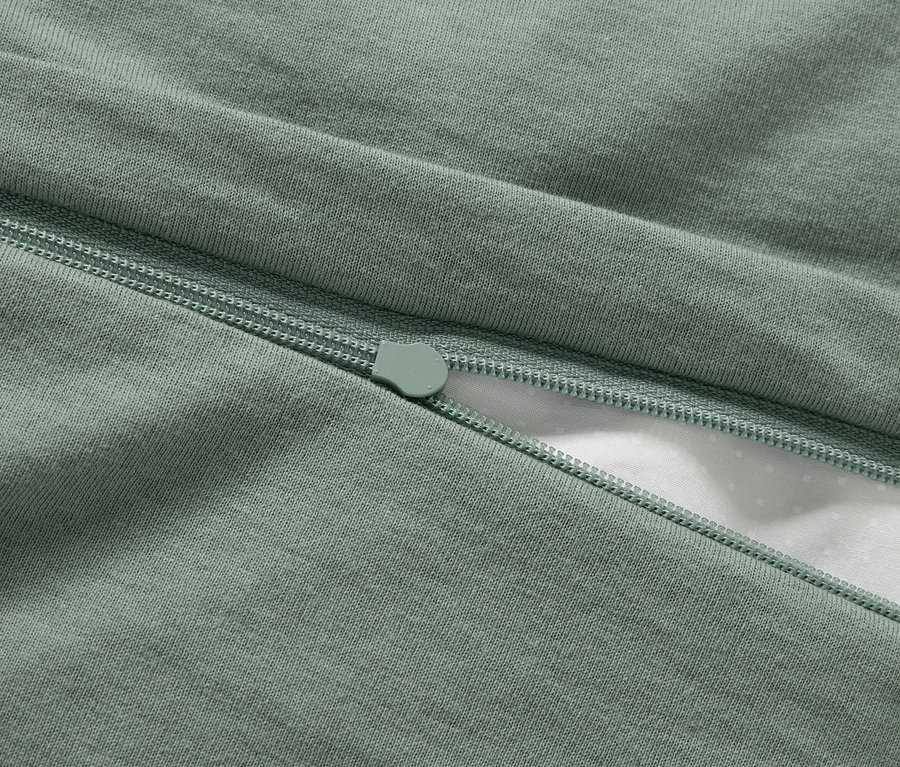 Gros plan d'une housse de couette verte avec une fermeture éclair.
