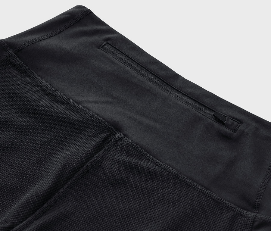 Gros plan d'un legging de trekking 3/4 noir avec une poche zippée à la taille.