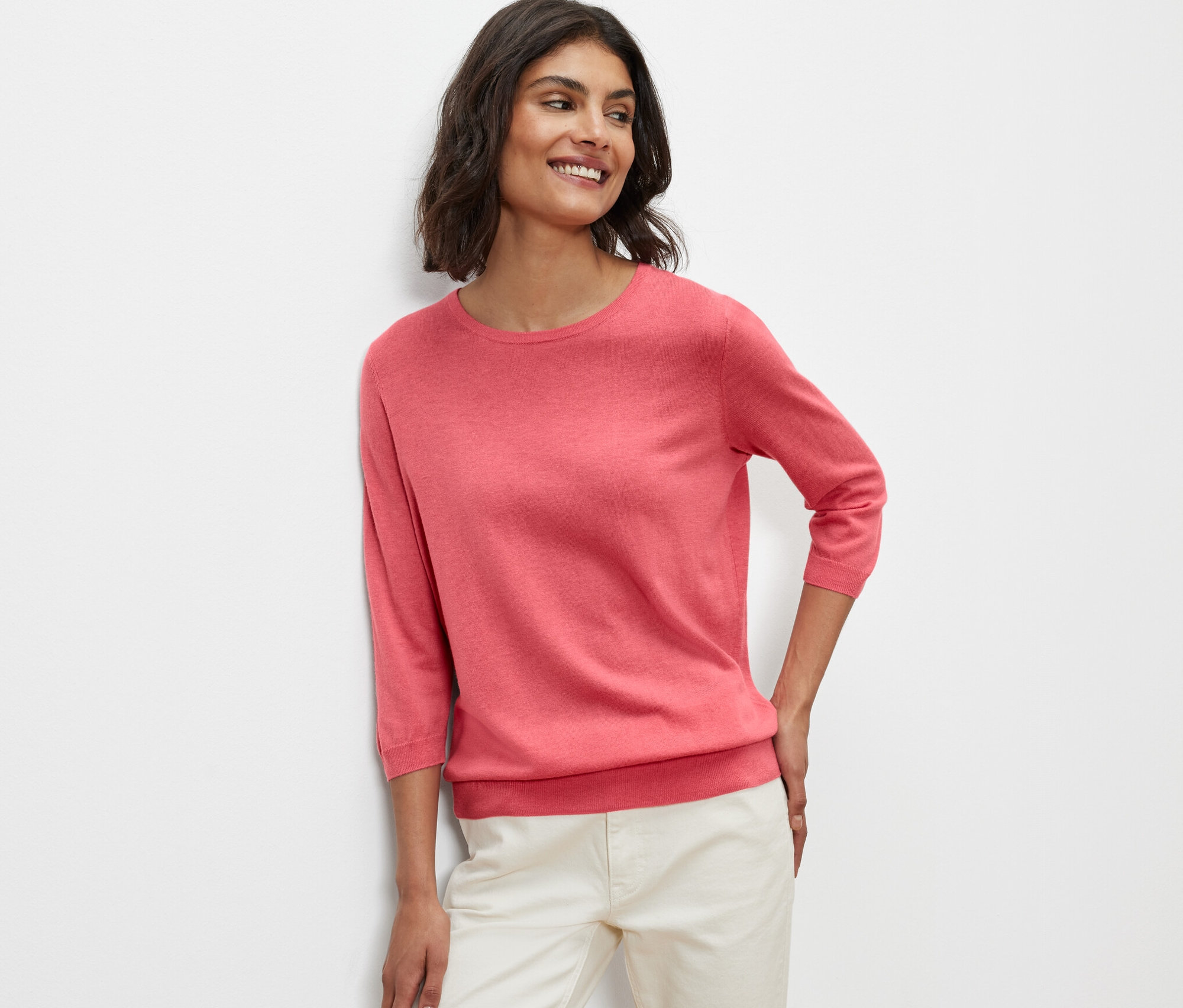 Femme posant en pull-over en maille fine avec soie, corail.