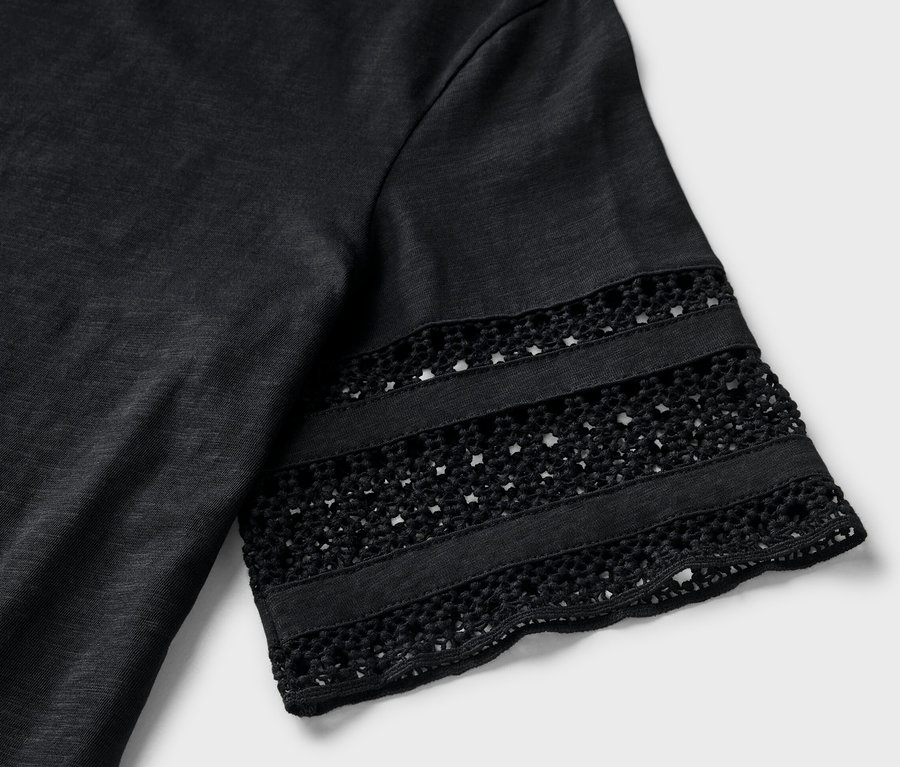 Détail d'un t-shirt noir avec broderie sur la manche.