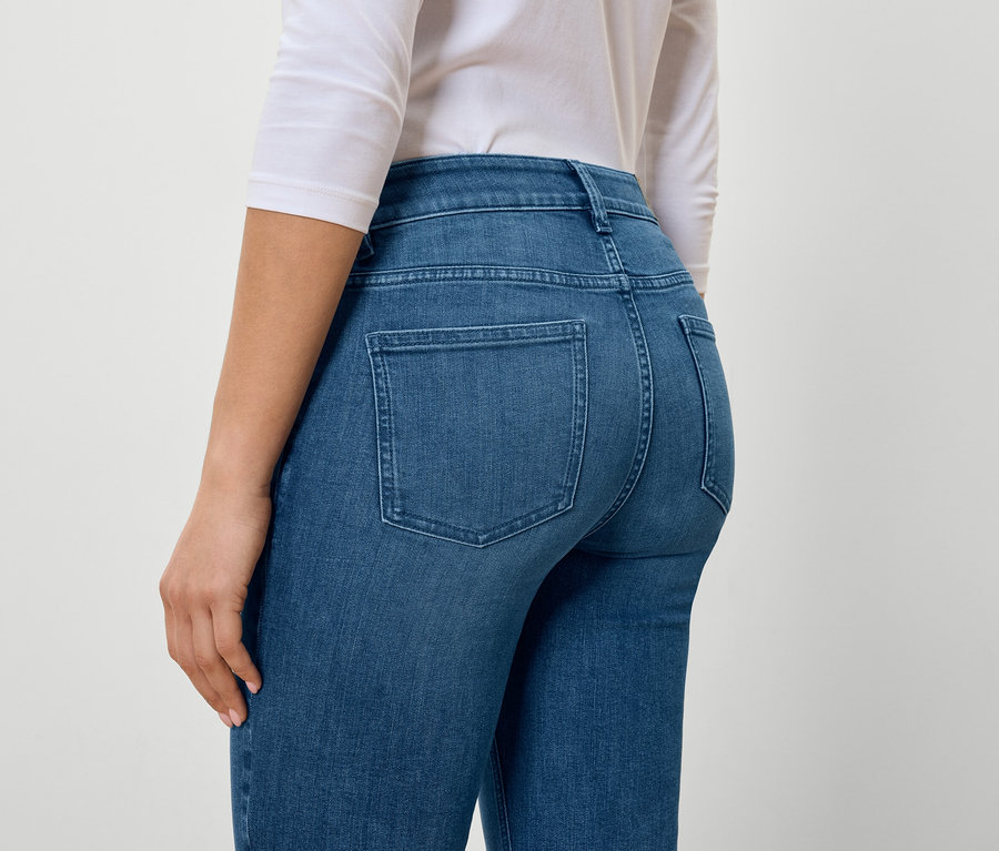 Vue arrière d'une femme portant un jean bleu et un t-shirt blanc.