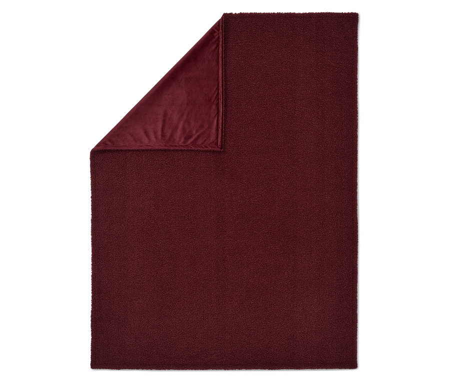 Une couverture bordeaux avec un coin replié, révélant une doublure en velours.