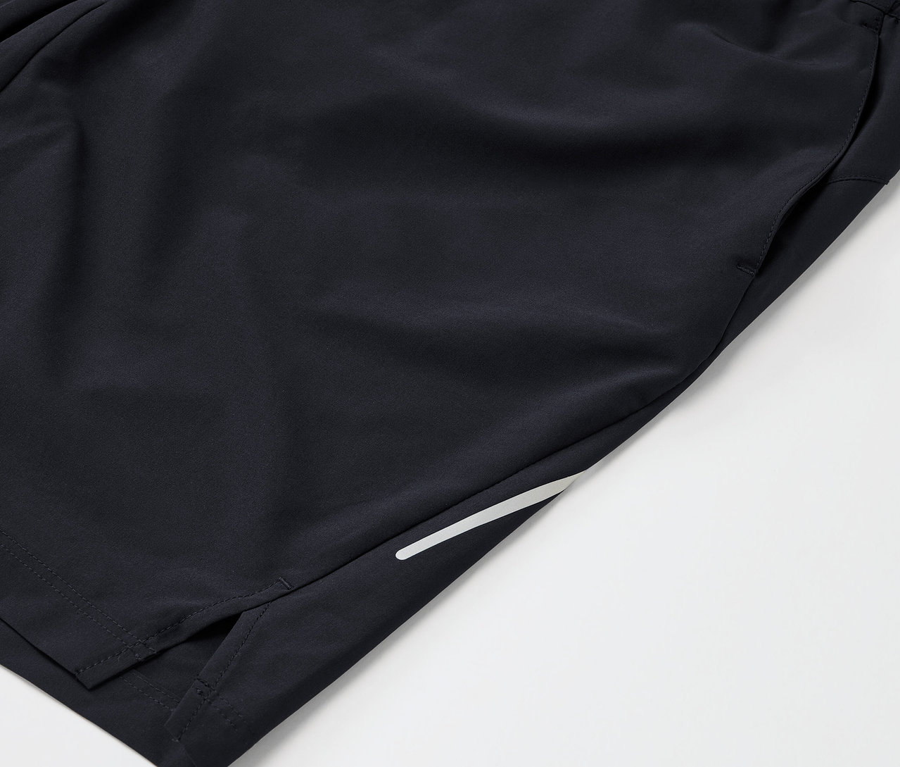 Gros plan sur un short de sport noir avec une poche et une bande réfléchissante.