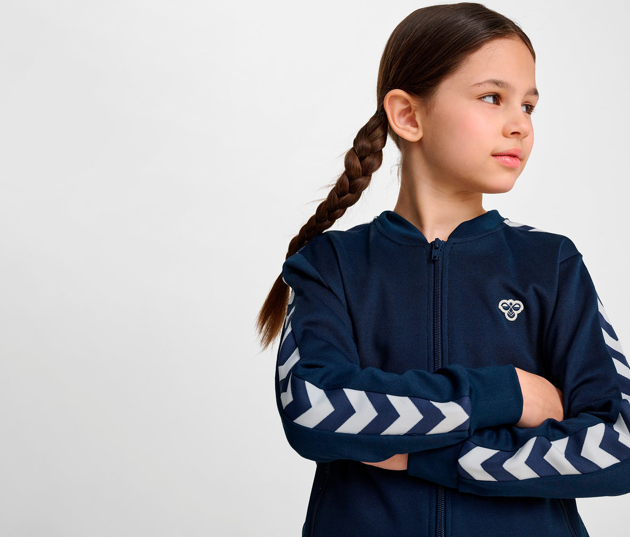 Une fille avec une tresse porte une veste zippée bleue HUMMEL HMLJR Archive Reg Poly.