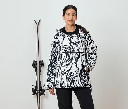 Femme en veste à motifs noirs et blancs se tenant à côté de skis.
