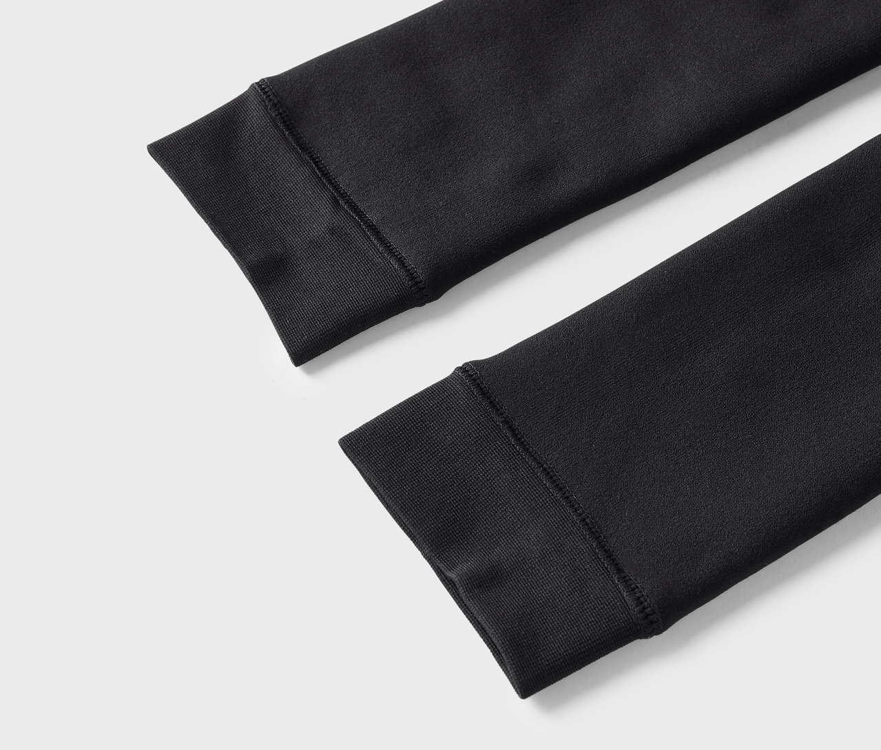 Détail de deux manches noires de sweat-shirt avec poignets côtelés.