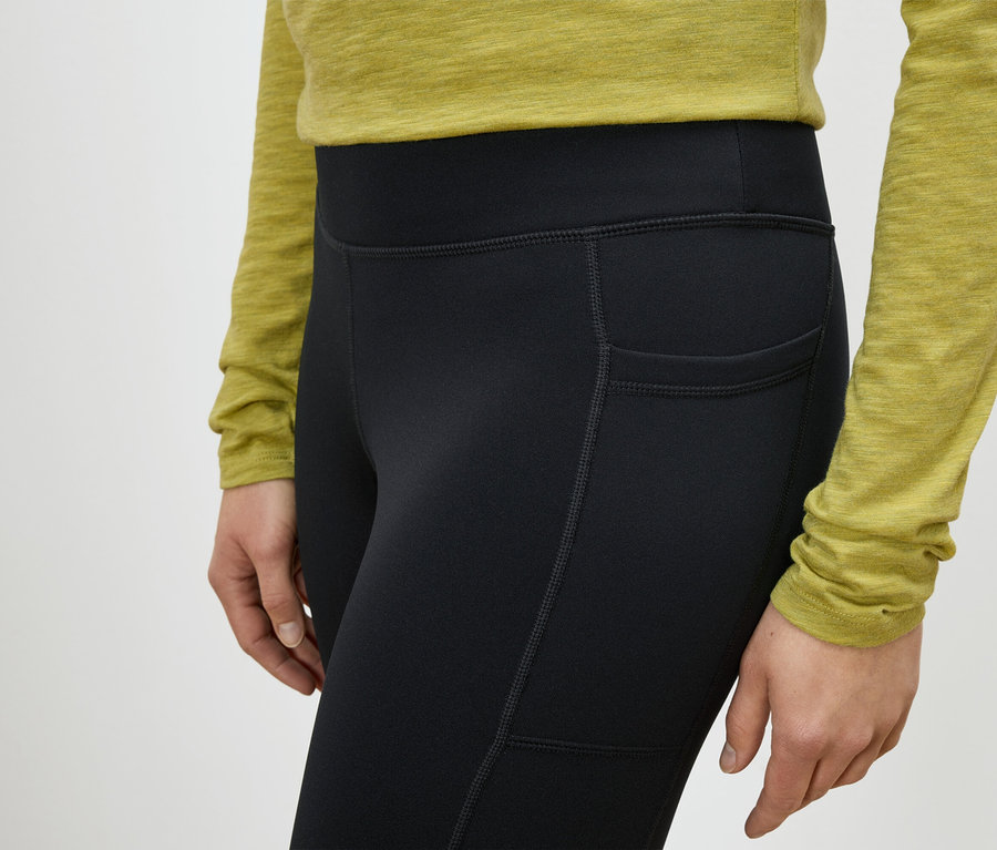 Une femme porte des leggings noirs avec une poche sur la cuisse.