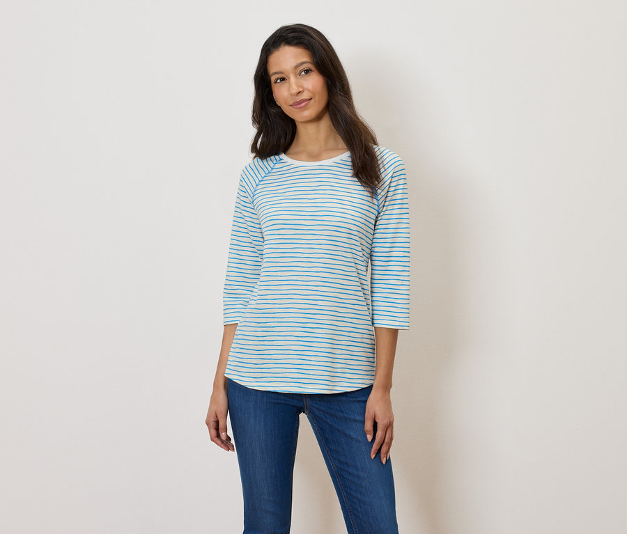 Femme portant un t-shirt à manches longues rayé bleu et blanc et un jean bleu.