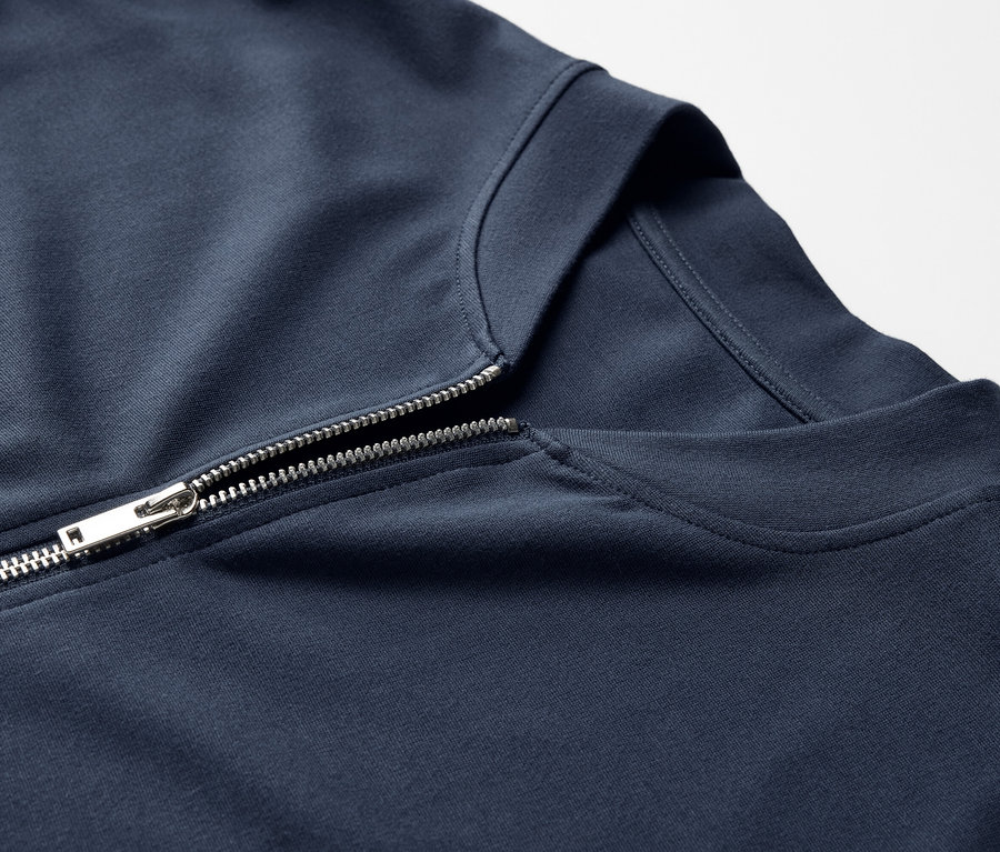 Gros plan sur une veste en sweat bleu marine avec une fermeture éclair argentée.