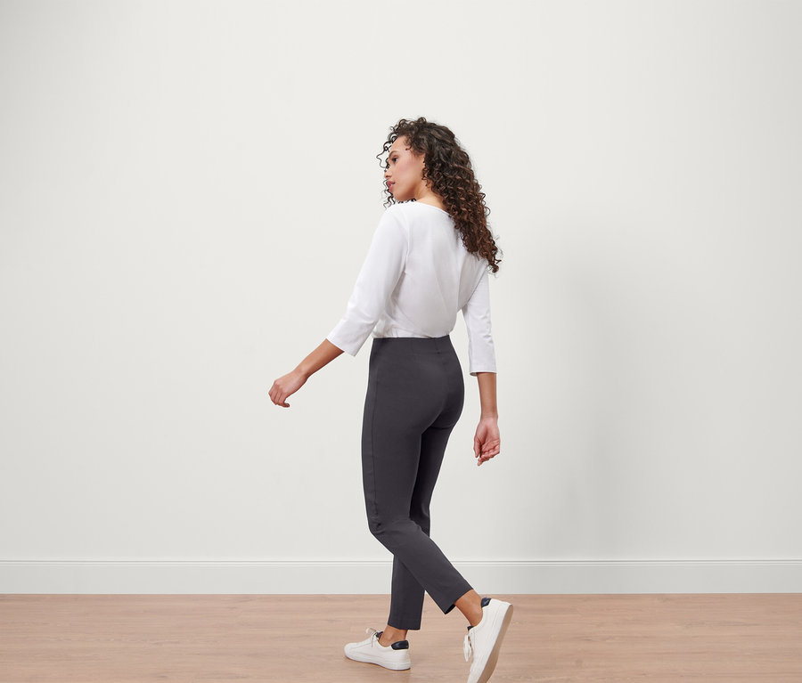 Femme portant un haut blanc et un pantalon stretch gris.