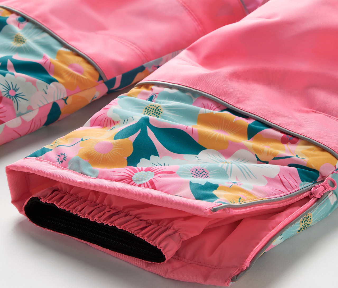 Détail d'un pantalon rose avec un motif floral et un ourlet élastique.