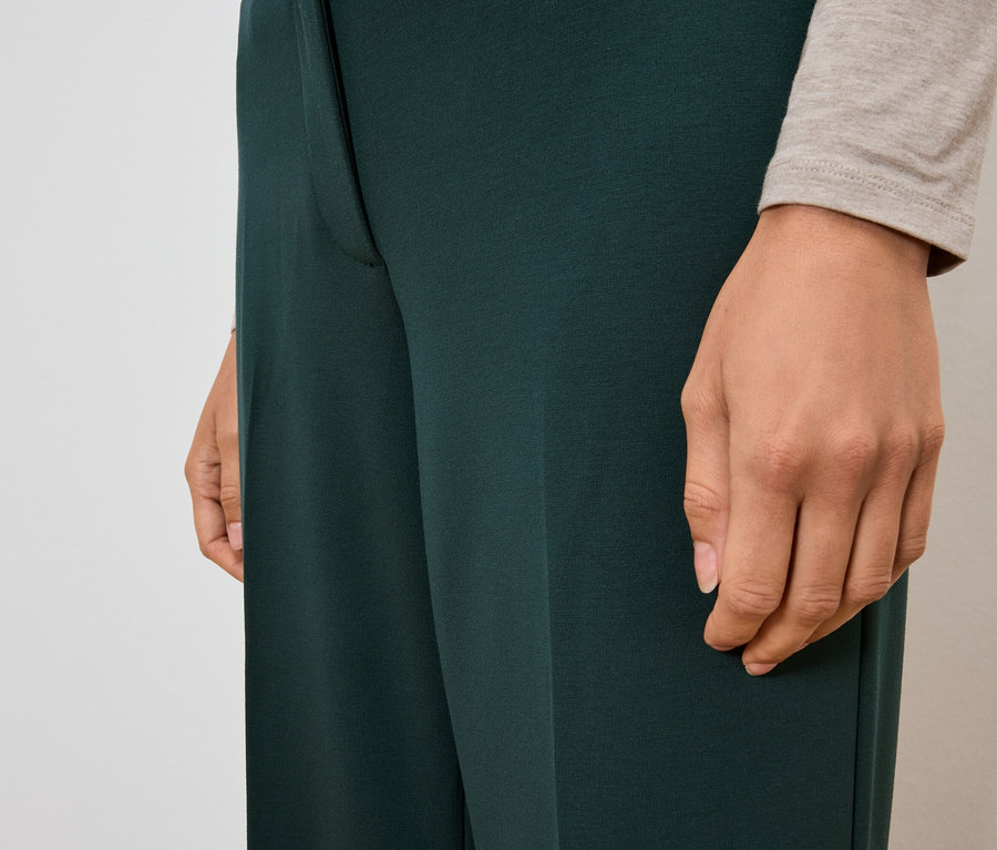 Gros plan d'une femme portant un pantalon vert foncé.