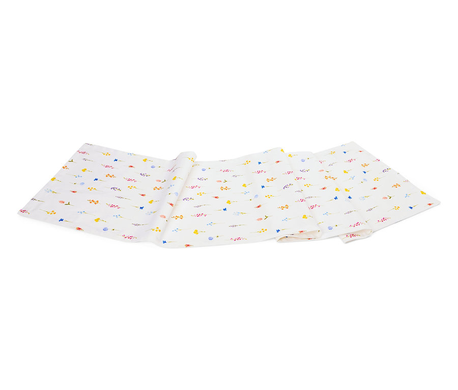 Un tissu blanc avec un motif de petites fleurs colorées est plié sur un fond blanc.