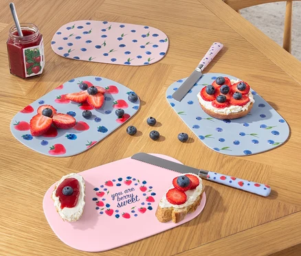Quatre planches à petit déjeuner avec des fruits et des couteaux sur une table en bois.
