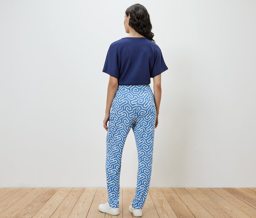 Femme vue de dos portant un pantalon en jersey imprimé bleu.