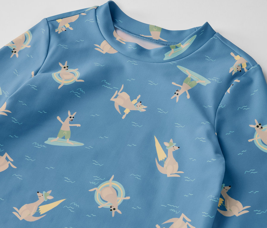 T-shirt bleu pour enfant avec indice de protection UV 80, imprimé avec des kangourous faisant du surf et nageant dans la mer.
