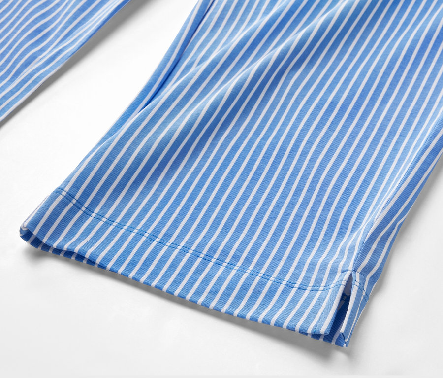 Détail d'un pantalon de pyjama rayé bleu et blanc.