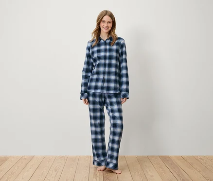 Une femme debout portant un pyjama à carreaux bleus.