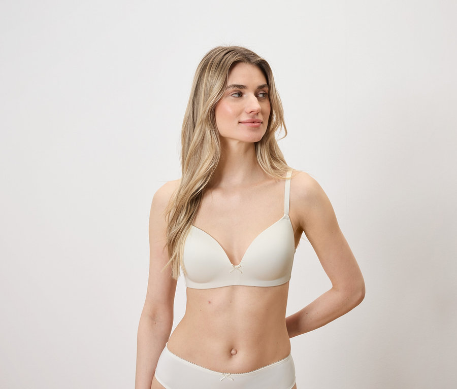 Femme aux cheveux blonds et à la peau claire posant en soutien-gorge et culotte clairs.