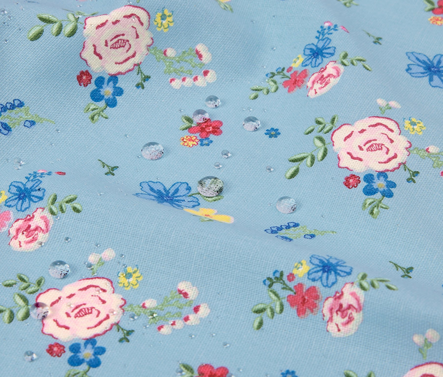Gros plan d'un tissu bleu clair à motif floral avec des gouttes d'eau.