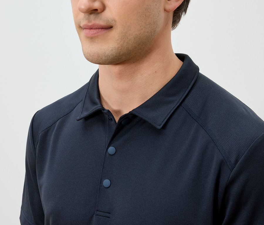 Gros plan d'un homme portant un polo bleu marine.
